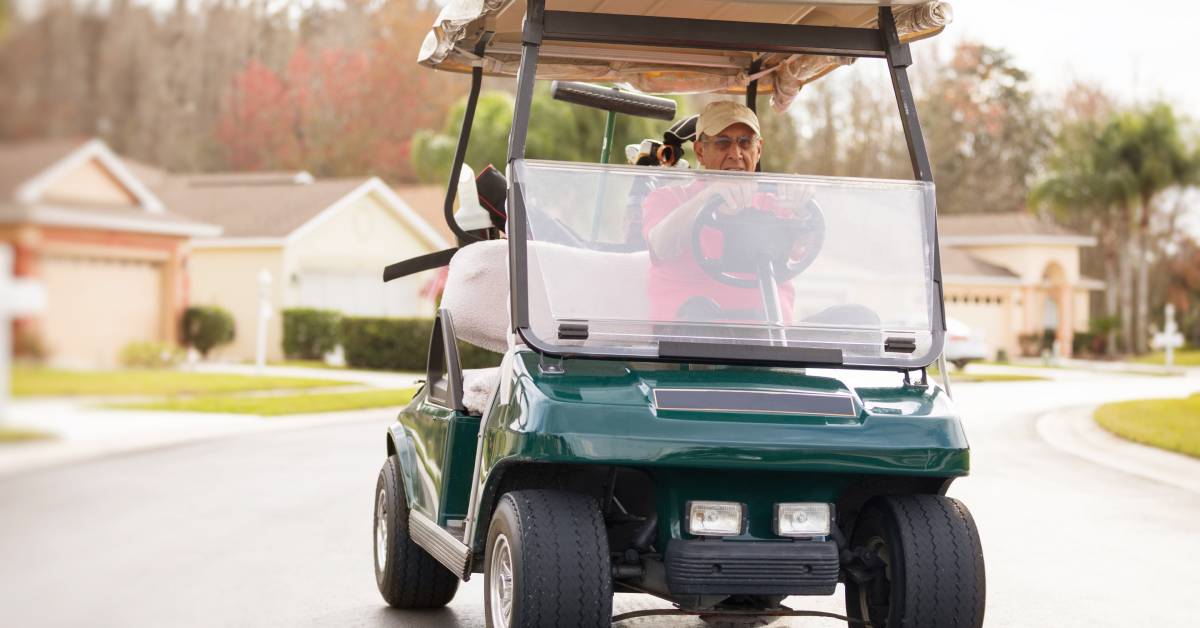 A senior citizen drives a golf cart through a residential neighborhood in Florida on their way to the beach.