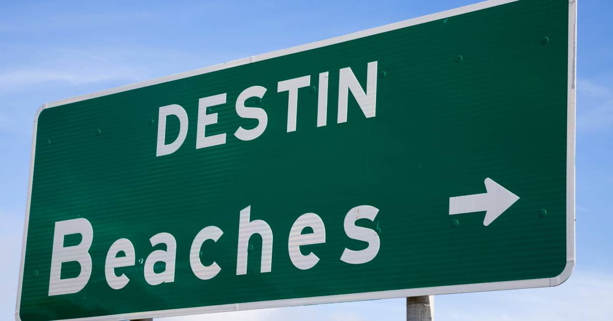 A large green road sign signals the location of Destin's beaches. An arrow points directions to the right.
