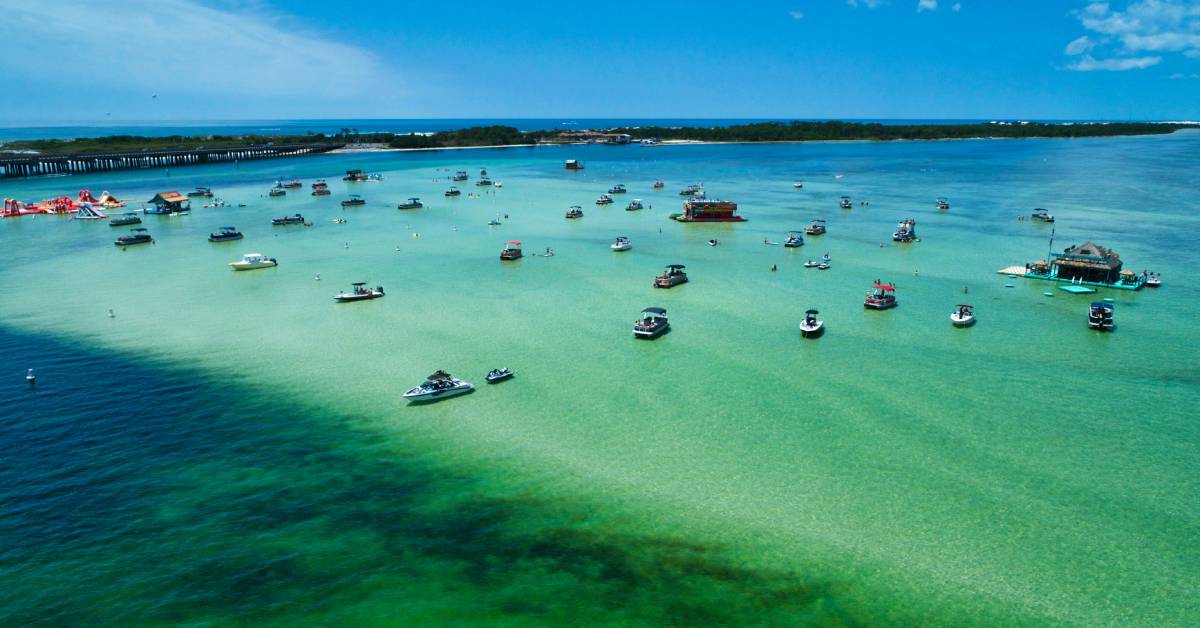 A group of boats anchored on Crab Island, a famous sandbar to find crabs. The water is a mix of deep blues and teal.